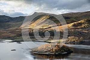 Stunning Autumn Fall landscape of Hawes Water with epic lighting and dramatic sunlight in Lake District