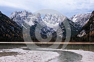 Stunning autumn landscape, alpine glacier lake and yellow pine trees, Landro lake with famous Cristallo mountain group in