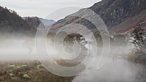 Stunning Autumn landscape sunrise image looking towards Borrowdale Valley from Manesty Park in Lake District with fog rolling