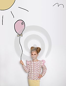 Stunning beautiful little girl with long blond hair standing on a white background and holds a balloon