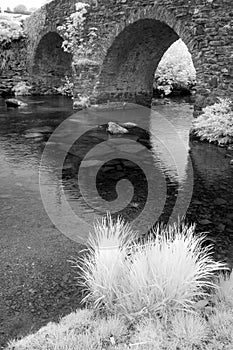 Stunning black and white infrared landscape image of old bridge