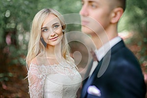 Stunning blonde bride with deep green eyes admires groom
