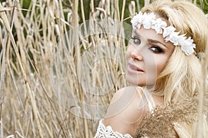 Stunning blonde natural woman swing on a swing on a tree wearing a spring dress