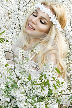 Stunning blonde natural woman swing on a swing on a tree wearing a spring dress