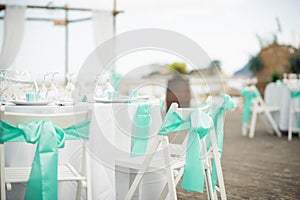 stunning blue trim decorates the back of these white folding chairs at this outdoor beach front reception