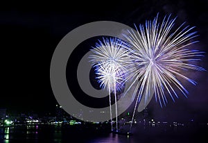 Stunning blue and white fireworks exploding into the night sky over the bay