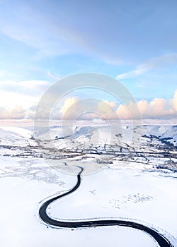Stunning blue winter snow pink clouds sky winding icy black road in mountains no people dramatic sky snowy landscape near Mam Tor
