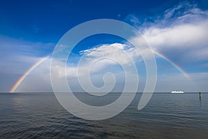 Stunning boat sailing in front of a beautiful rainbow arching over the Chesapeake Bay