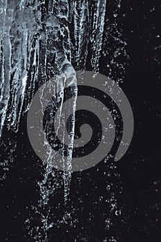 Closeup of the waterfall icicles on the background of rock