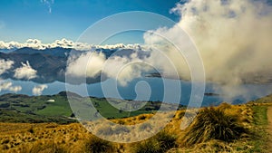 Stunning cloudy views of the bays of Lake Wanaka and the snow capped Southern Alps from the Roys Peak mountain track