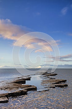 Stunning colorful sunrise over ocean landscape scene with cliffs and beautiful cloud formations