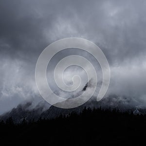 Stunning detail landscape images of snowcapped Pen Yr Ole Wen mountain in Snowdonia during dramatic moody Winter storm