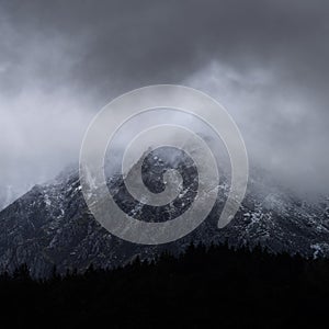 Stunning detail landscape images of snowcapped Pen Yr Ole Wen mountain in Snowdonia during dramatic moody Winter storm