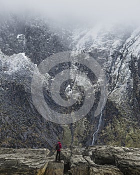 Stunning dramatic landscape image of snowcapped Glyders mountain range in Snowdonia during Winter with menacing low clouds hanging