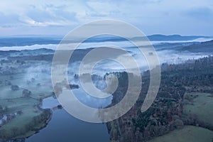 Stunning drone aerial landscape image of cloud inversion around Esthwaite Water in Lake District during Spring sunrise