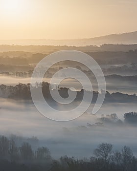 Stunning foggy English rural landscape at sunrise in Winter with