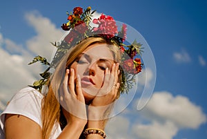 Stunning girl in flower wreath dreaming on blue