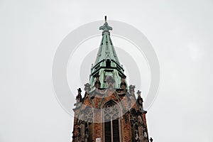 A stunning Gothic church spire with intricate architectural details, aged brickwork, and a patina-covered roof, set photo
