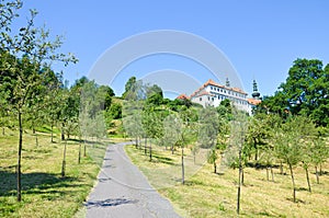 Stunning green gardens on Petrin Hill in the center of Prague, the Czech capital. Historical building with towers in background.