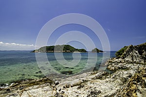 Stunning image rocky beach surrounded by clear blue sea water at Kapas Island, Malaysia.