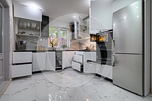 A stunning kitchen with a white, modern design, a luxurious marble floor, and pull-out shelves
