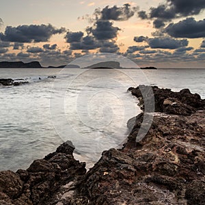Stunning landscape dawn sunrise with rocky coastline and long exp