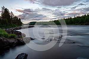 Stunning landscape illuminated by a pink sunset over a tranquil river in Norrland
