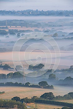 Glorious landscape image of layers of mist rolling over South Downs National Park English countryside during misty Summer sunrise