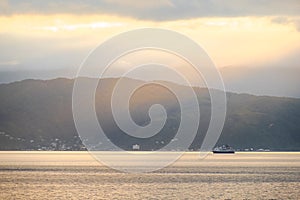 Stunning landscape sunrise in the morning. Ferry on the sea. Golden light go through the cloud to the mountain and sea. I