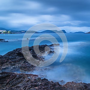 Stunning landscape at twilight dawn with rocky coastline and lon