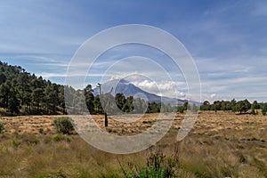 Stunning landscape view of a forested area with volcan popocatepetl on the horizon top in clouds photo