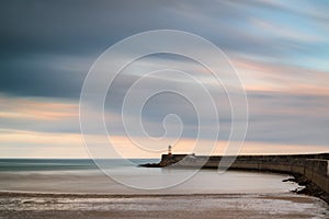 Stunning long exposure landscape lighthouse at sunset with calm