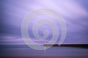 Stunning long exposure landscape lighthouse at sunset with calm