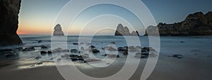 Stunning long exposure shot of the waves crashing against the rocky shore of Camilo Beach in Algarve