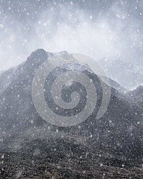 Stunning moody dramatic Winter landscape image of snowcapped Y Garn mountain in Snowdonia