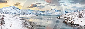 Stunning morning view of Torsfjorden fjord with cracked ice and snowy mountain peaks at background