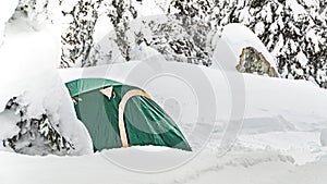 Stunning mountain landscape with green tourism tent on snow, covered snowstorm