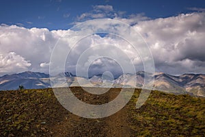 Stunning mountain landscape. Thunderstorm front over the mountain range, sun`s rays shine through fluffy clouds. Beautiful sky.