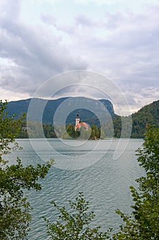 Stunning nature landscape of Bled Lake with St. Marys Church of Assumption on small island. Natural frame form green leaves