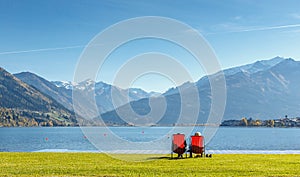 Stunning Nature Landscape. Romantic couple, near a lake sitting on chairs. Panoramic view of beautiful mountain landscape in Alps