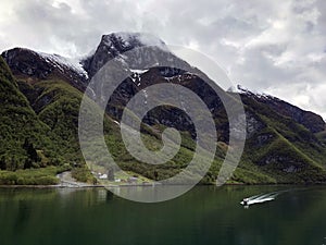 Stunning Norwegian sea landscape with Naeroyfjord (NÃ¦rÃ¸yfjord), high green mountains, green sea water, and ship