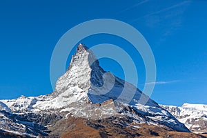 Stunning panorama view of the famous Matterhorn peak of Swiss Alps on sunny autumn day with snow and blue sky, from the train