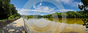 A stunning panoramic shot of the vast still silky brown water of the Chattahoochee river with a long wooden boardwalk