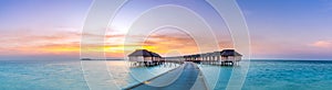 Stunning panoramic sunset Maldives. Luxury resort villas seascape with soft led lights under colorful sky. Amazing twilight sky