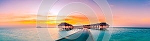 Stunning panoramic sunset Maldives. Luxury resort villas seascape with soft led lights under colorful sky. Amazing twilight sky