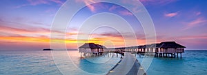 Stunning panoramic sunset Maldives. Luxury resort villas seascape with soft led lights under colorful sky. Amazing twilight sky