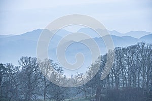 Stunning peaceful landscape image of misty Spring morning over Windermere in Lake District and distant misty peaks