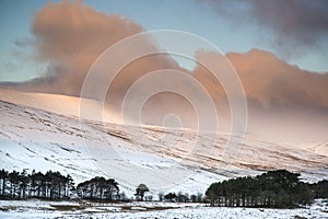 Stunning pink sunrise over mountain snow covered Winter landscape