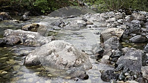 Stunning river flowing through large rocks with vivid green vegetation in the background