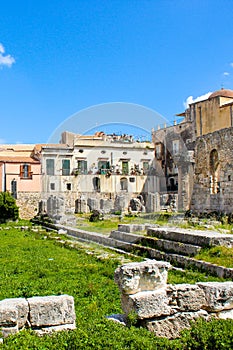 Stunning ruins of the Temple of Apollo in Ortigia Island, Syracuse, Sicily, Italy captured on a vertical photo with blue sky.